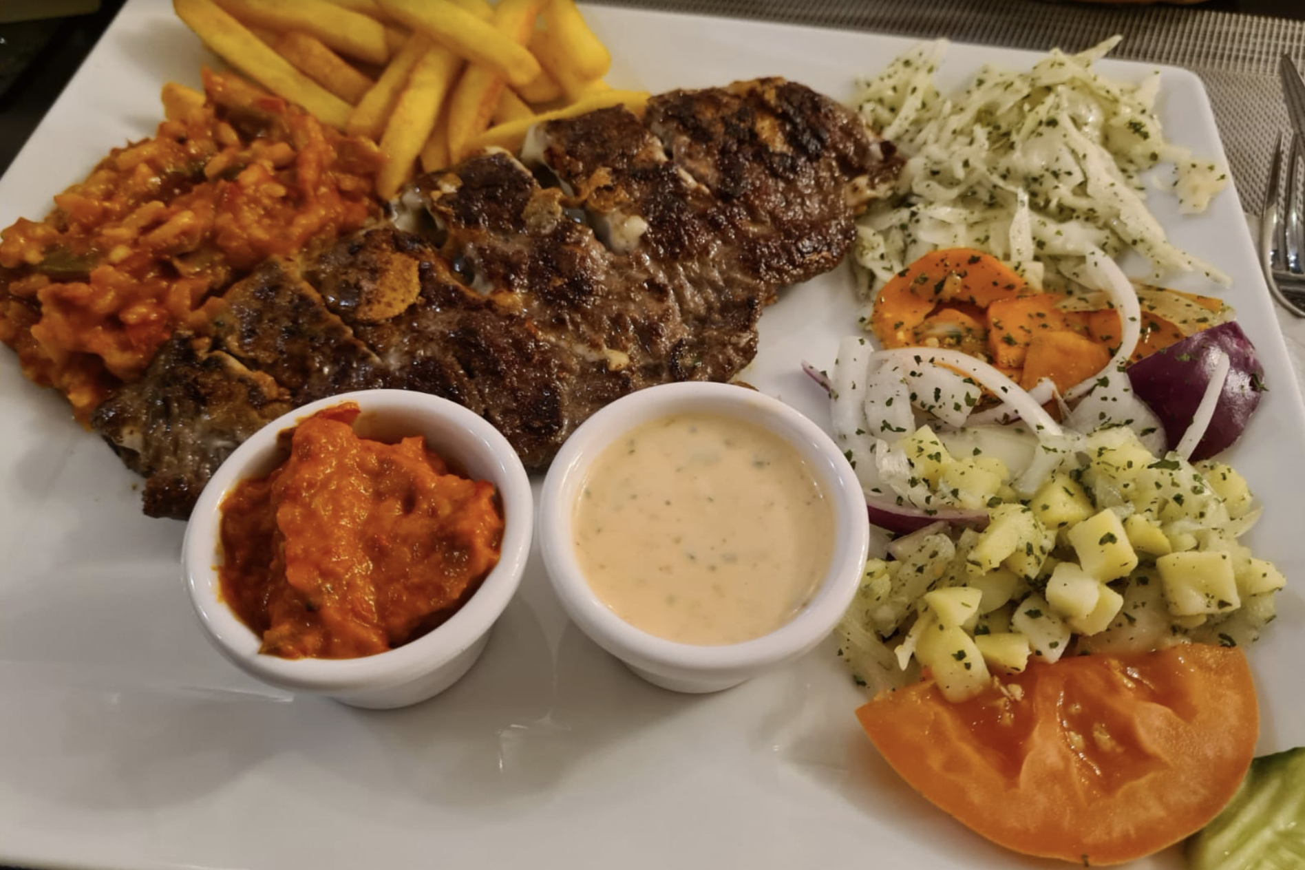 Großer Pljeskavica-Teller mit Pommes, Salat und hausgemachten Soßen – Schillerhof Pnishi