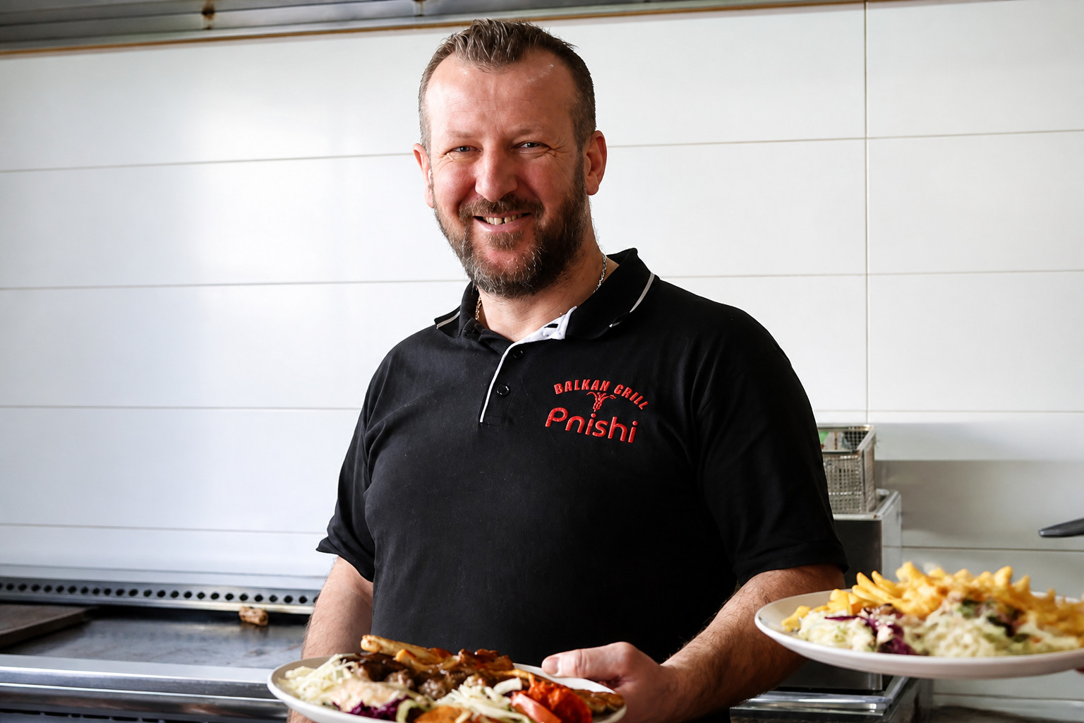 Chef Ylber Pnishi mit frisch angerichteten Grilltellern – Restaurant Schillerhof Pnishi